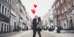 couple holding balloons kissing in the middle of the street