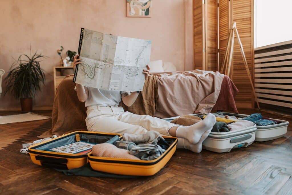 lady reading newspaper next to open luggages